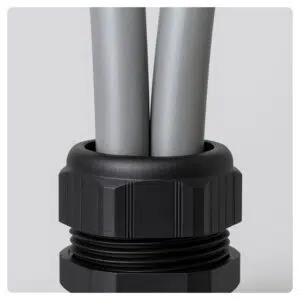 Close-up of a plastic cable gland with two grey 25mm² PVC meter tails entering a metal consumer unit.
